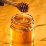honey drizzling from a dipper into a jar